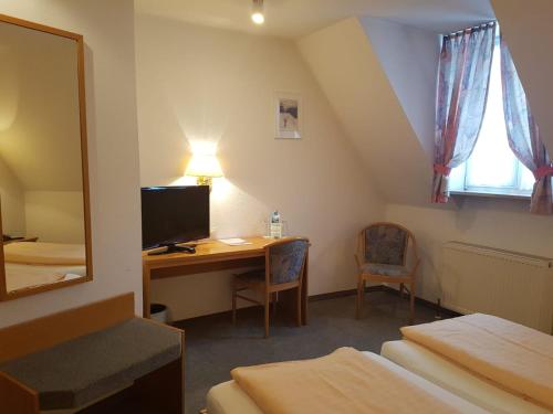 a hotel room with a desk and a television at Landgasthof Hotel Grüner Baum in Nürnberg