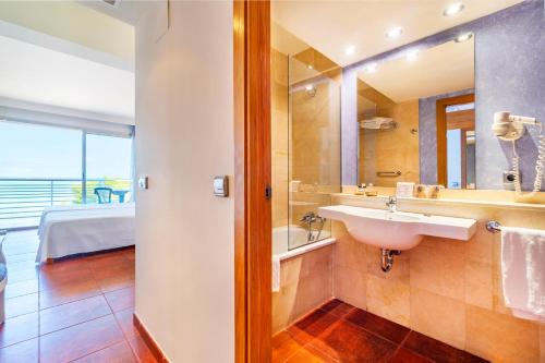 ein Bad mit einem Waschbecken und einem Spiegel in der Unterkunft Hotel Na Forana in Cala Ratjada