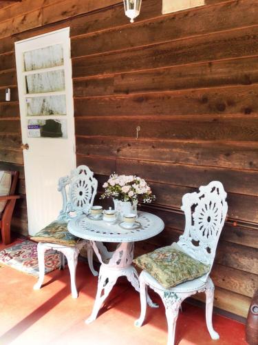 two chairs and a table with flowers on a porch at Curtis Cottage in Mount Tamborine