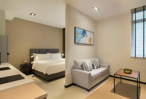 a bedroom with a bed and a couch and a chair at Momentus Serviced Residences Novena in Singapore