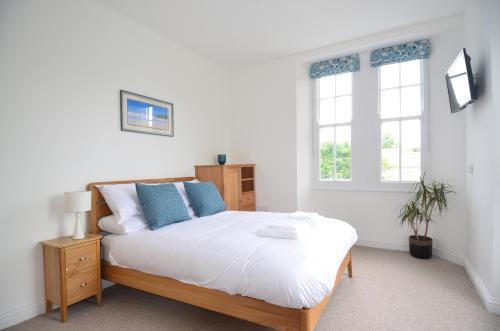1 dormitorio con 1 cama con sábanas blancas y almohadas azules en Towennan - four bedroomed apartment in quiet seaside village., en Gwithian