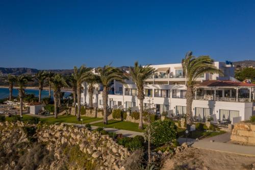 Vrachia Beach Hotel & Suites - Adults Only في بافوس: منظر خارجي لمبنى به نخيل
