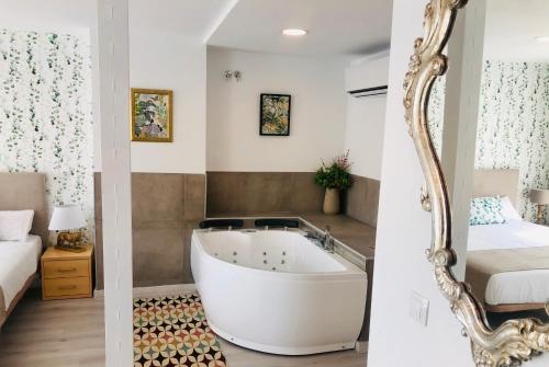 uma casa de banho com uma banheira, uma cama e um espelho. em Hotel Finca Alcamino em Mompía