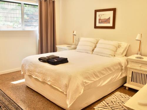 Un dormitorio con una cama blanca con dos bolsas encima. en Malibu Apartment - Peregian Beach, en Peregian Beach