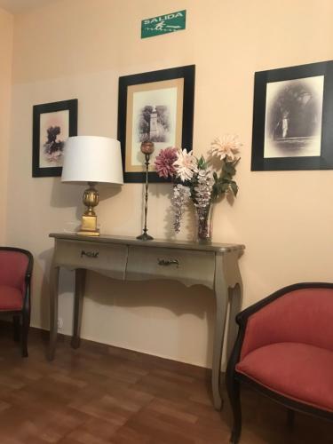 a table with a lamp and flowers on it at Hostal Plaza in Marmolejo
