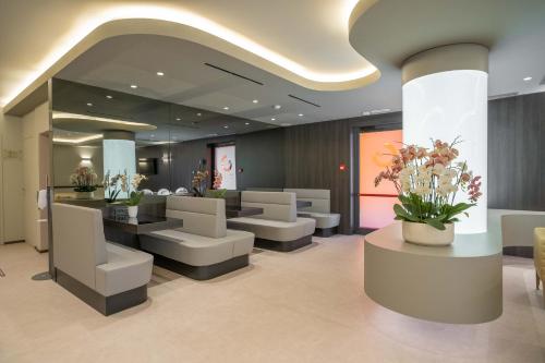 a lobby with a waiting room with white chairs and flowers at Hotel Guerro in Castelvetro di Modena