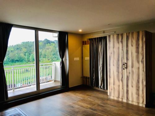 a living room with a large window and a balcony at Sharada Residency in Somvārpet