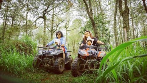 three people riding on atvs in the woods at Lawu Forest Camp in Sarangan