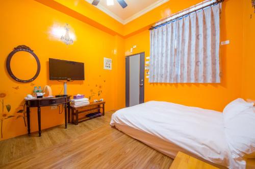 a bedroom with orange walls and a bed and a television at Chang-an House B&B in Hualien City