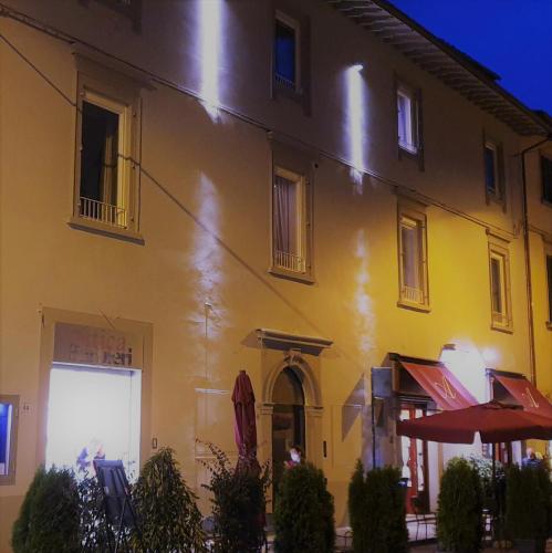a large yellow building with tables and umbrellas in front at Palazzo 42 - Boutique Hotel & Suites in Pistoia