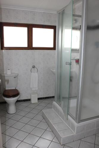 a bathroom with a toilet and a glass shower at Hansa Hotel Swakopmund in Swakopmund