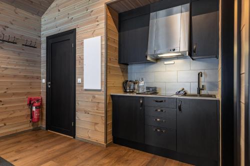a kitchen with black cabinets and a wooden wall at Skigaarden in Hemsedal