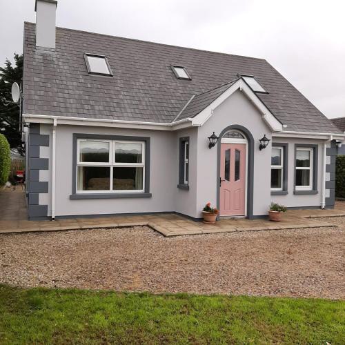 une maison avec une porte rose dans une allée dans l'établissement Suaimhneas, à Falcarragh