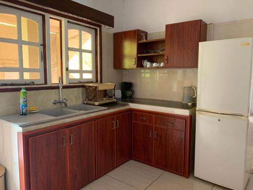 a kitchen with wooden cabinets and a white refrigerator at Orchid Sunset Guest House in Baie Lazare Mahé