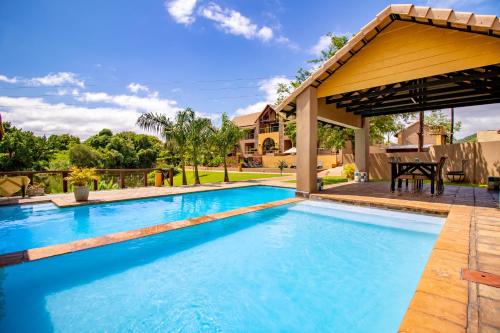 a swimming pool with a gazebo next to a house at Nkomazi Kruger Lodge & Spa in Malelane