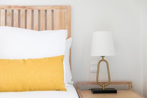 Una cama con una almohada amarilla y una lámpara sobre una mesa en Feelathome Goya Apartments, en Madrid