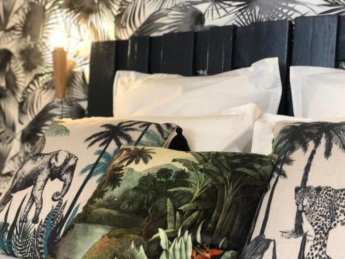 einen Haufen Kissen auf einem Bett mit Palmen in der Unterkunft Appartement centre-ville avec terrasse INDUS in Vannes