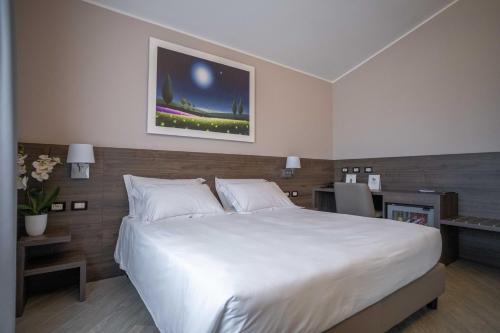 a bedroom with a large white bed and a painting on the wall at Hotel Guerro in Castelvetro di Modena