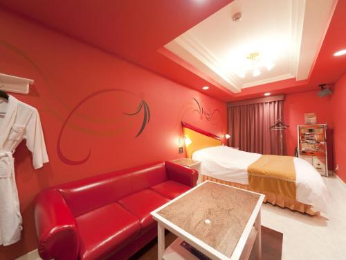 a red room with a bed and a red couch at Hotel Fine Garden Suzuka in Suzuka