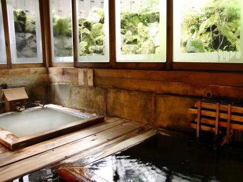 a bath tub in a room with windows at Kinokuniya Ryokan in Hakone