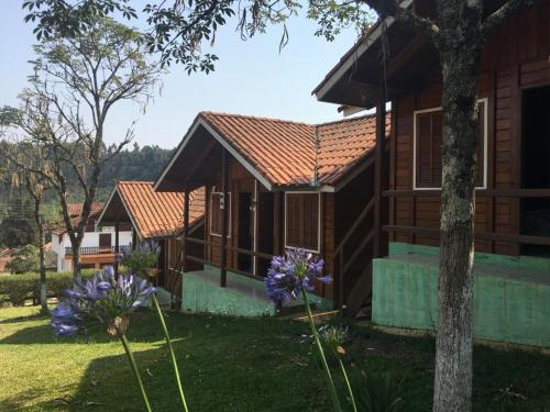 uma fila de casas rústicas com flores roxas à sua frente em Chalés Eucaliptos em Monte Verde