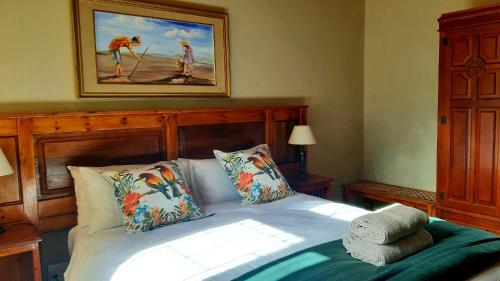 a bedroom with a bed and a painting on the wall at Bluebell Country House in Dullstroom
