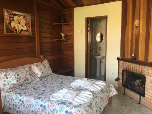 Un dormitorio con una cama y una chimenea. en Chalés Eucaliptos -Recanto da Neusa-, en Monte Verde