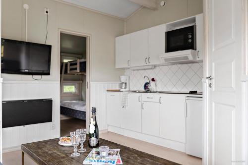 a kitchen with white cabinets and a table with wine glasses at First Camp Hagön-Halmstad in Halmstad