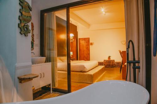 a bathroom with a bedroom with a bed and a tub at SANSE Boutique Hotel in El Nido