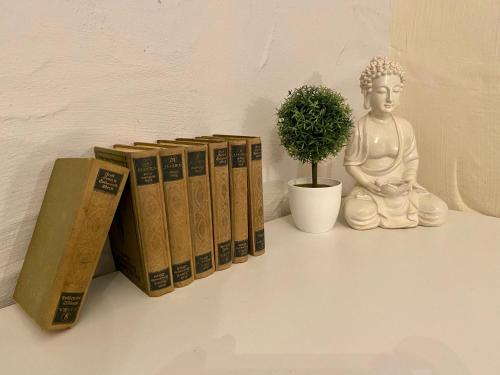 a group of books and a buddha statue and a plant at Eifelstein, Apartment mit Whirlpool und Ofen in Dahlem