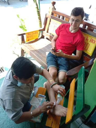 two people sitting on a bench with a man holding a bottle at Jay Guesthouse and Restaurant (adult only) in Chiang Mai