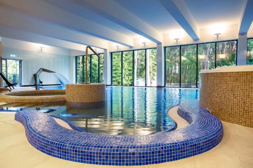 duży basen z niebieską podłogą wyłożoną kafelkami i oknami w obiekcie Hotel Orle w Gdańsku