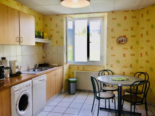 une cuisine avec une table et des chaises et une fenêtre dans l'établissement Gîte Léonline sur les hauteurs de Masevaux -au pied des Vosges, à Masevaux