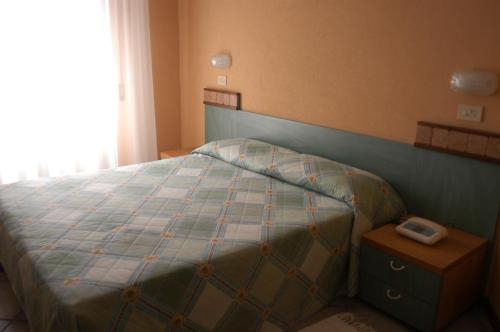 a bedroom with a bed with a phone on a night stand at Hotel Maré - Valentini Family Village in Bellaria-Igea Marina