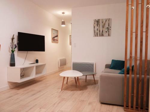 ein Wohnzimmer mit einem Sofa und einem Tisch in der Unterkunft Appartements Aux Portes d'Alès - Centre Ville in Alès