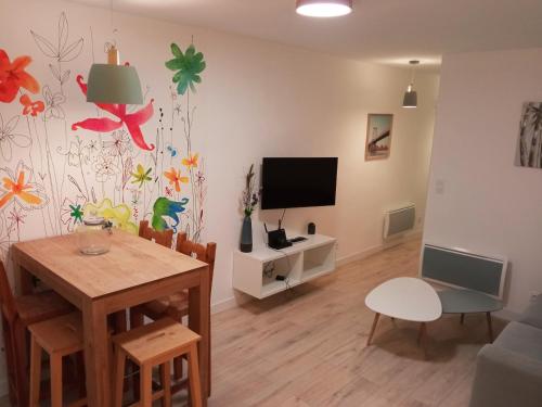 ein Wohnzimmer mit einem Tisch und einem TV in der Unterkunft Appartements Aux Portes d'Alès - Centre Ville in Alès