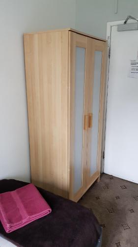 a bedroom with a wooden cabinet and a pink blanket at Hour Glass Hotel in London