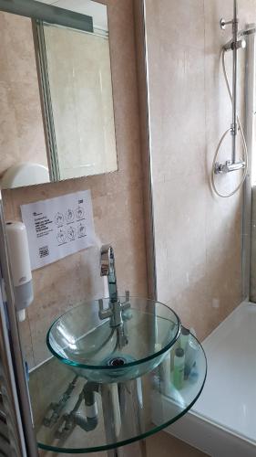 a glass sink in a bathroom with a shower at Hour Glass Hotel in London