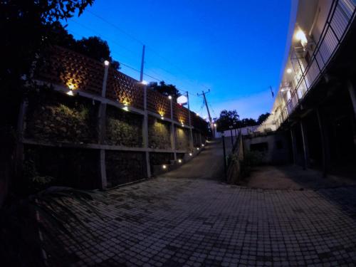 an empty street at night with lights on a fence at Hill Country Villa in Kandy