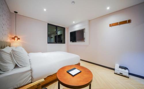 a small bedroom with a bed and a table at The Stone Bridge Hotel Dongnae in Busan
