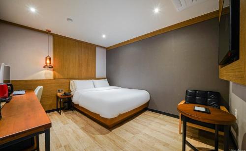 a bedroom with a bed and a table and a desk at The Stone Bridge Hotel Dongnae in Busan