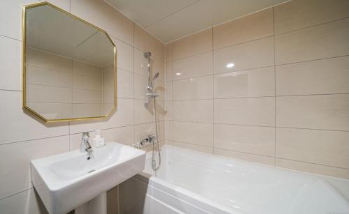a bathroom with a sink and a tub and a mirror at The Stone Bridge Hotel Dongnae in Busan