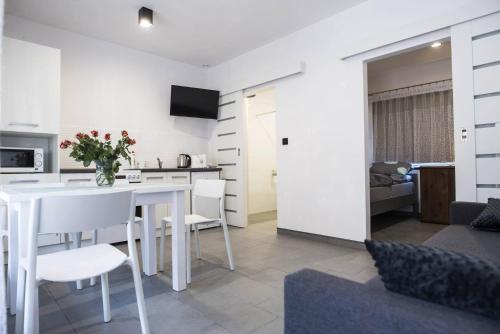 eine Küche und ein Wohnzimmer mit einem weißen Tisch und Stühlen in der Unterkunft Jurajskie Apartamenty in Żarki