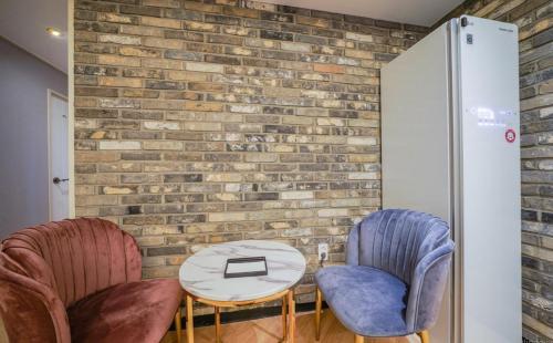 two chairs and a table in front of a brick wall at The Stone Bridge Hotel Dongnae in Busan