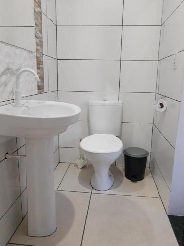a white bathroom with a toilet and a sink at Pousada Braga in Palmas