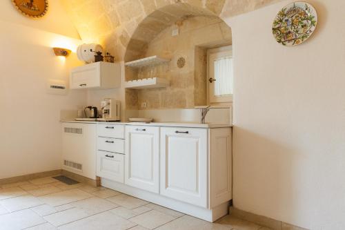 cocina con armarios blancos y suelo de baldosa en La Corte Dei Pastori, en Matera