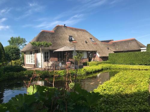 a thatched house with a pond in front of it at Appartement de Tuinkamer in Ter Apel