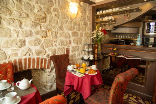 Hotel Du Beaumont في باريس: غرفة طعام مع طاولة وجدار حجري