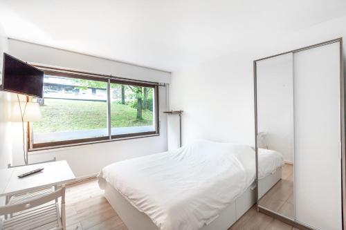 a white bedroom with a bed and a window at Georges Sand in Châtenay-Malabry