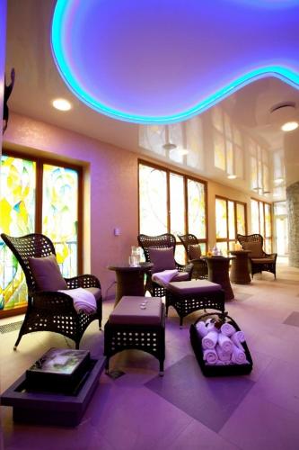 a room with chairs and tables and a purple ceiling at Hotel Ambiente Wellness & Spa in Karlovy Vary